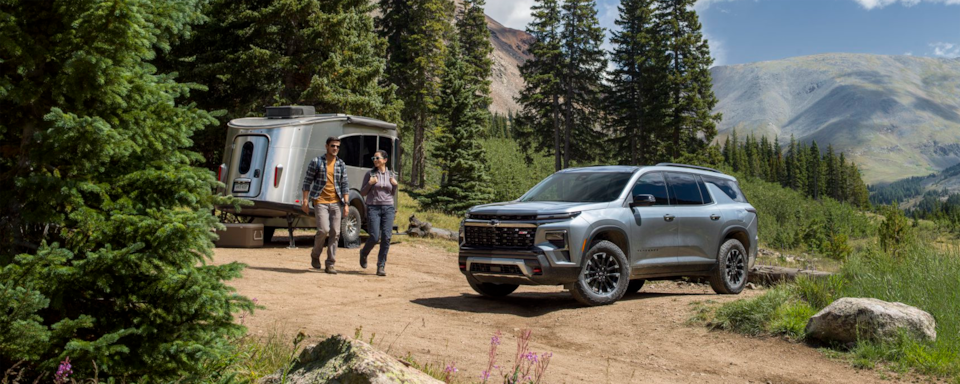 Two people walking near a 2025 Chevrolet Traverse SUV parked outdoors.