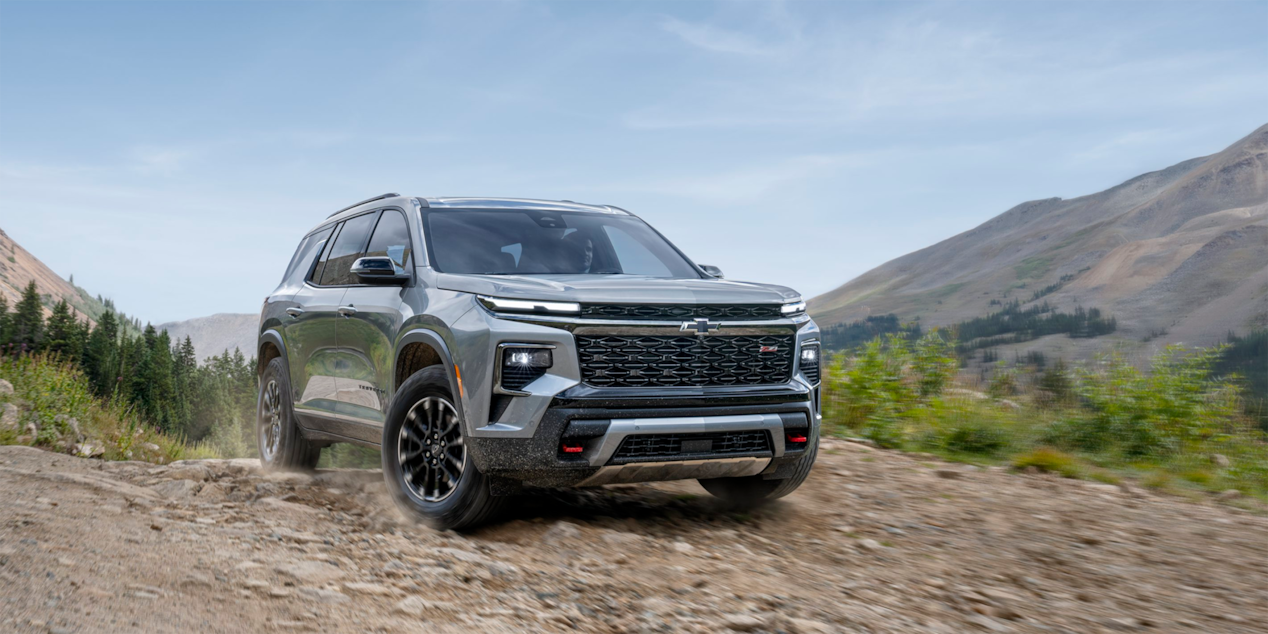 Front-side view of the 2025 Chevrolet Traverse SUV driving on a dirt path.