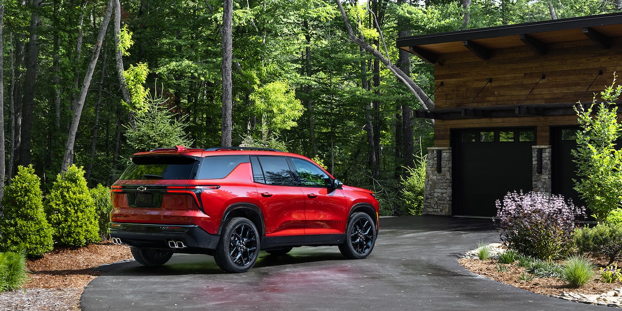Back-side view of the 2025 Chevrolet Traverse SUV parked outside a wooden house.