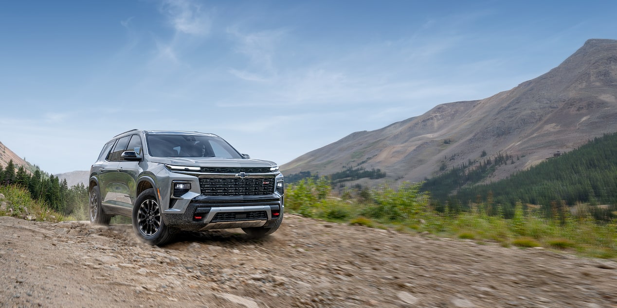Front-side view of the 2025 Chevrolet Traverse SUV driving alone outdoors on a sunny day.