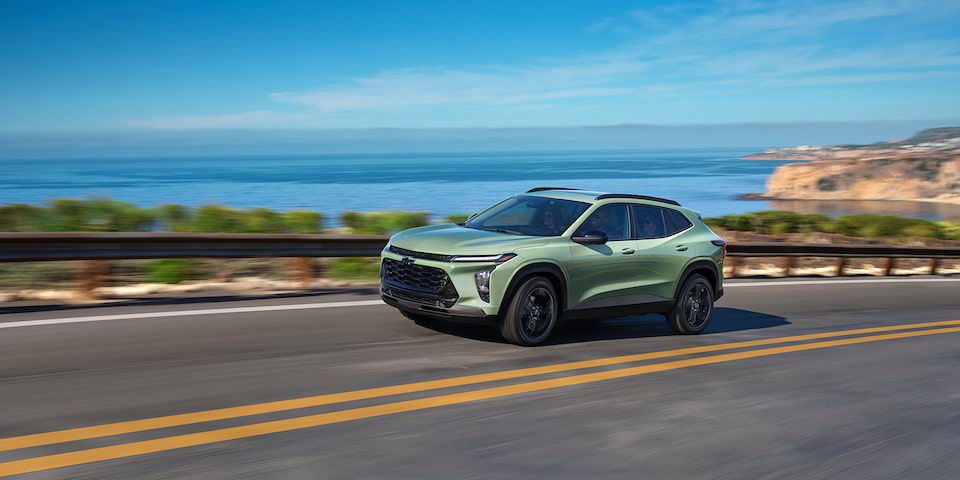 The 2025 Chevrolet Trax ACTIV driving swiftly down a waterfront road.