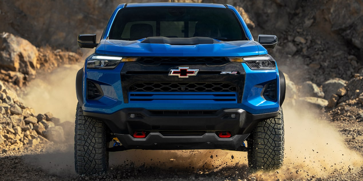 Front view of a blue 2025 Chevrolet Colorado skidding on a rocky terrain.