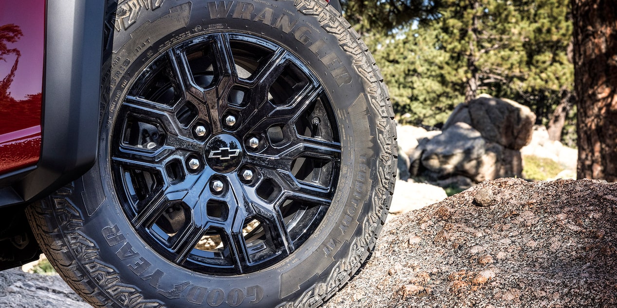 Close up view of the wheels of the 2025 Chevrolet Colorado parked on a dusty terrain.