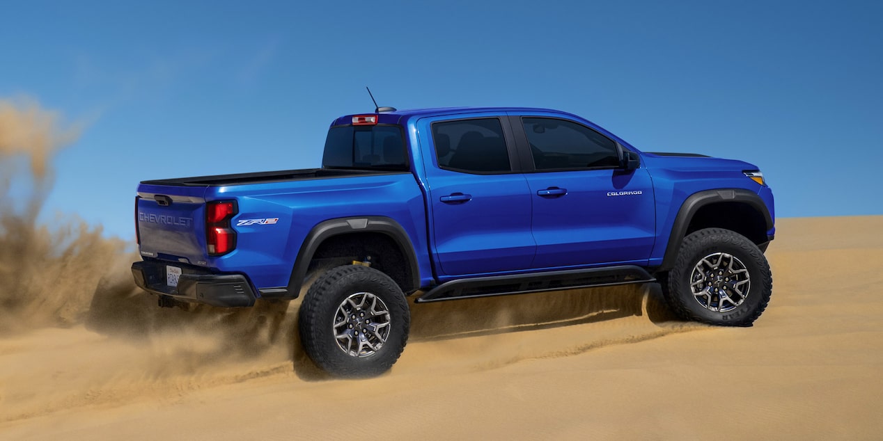 Side view of the 2025 Chevrolet Colorado driving upward on a desert.