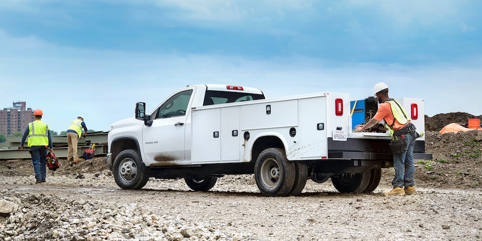 Un travailleur de la construction met du matériel dans la caisse utilitaire du châssis-cabine Chevrolet Silverado 3500 HD 2025.