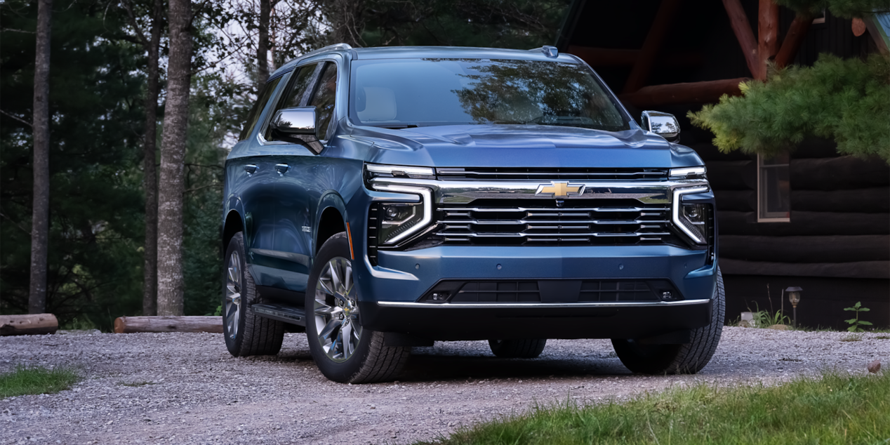 Front-side view of the 2025 Chevrolet Tahoe parked alone in front of a cabin.