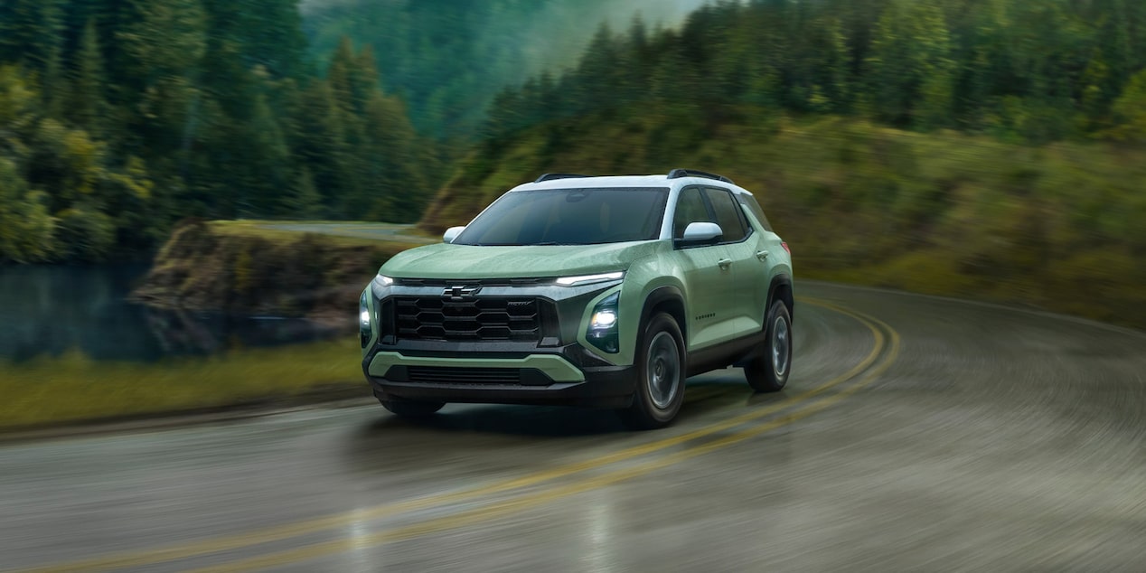 Un Chevrolet Equinox 2026 en mouvement sur une route mouillée dans la forêt.