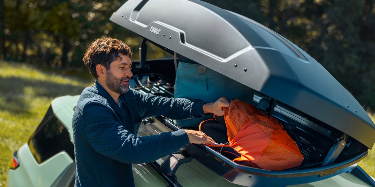 Side view of a person stowing belongings on the trunk of the 2026 Chevrolet Equinox.