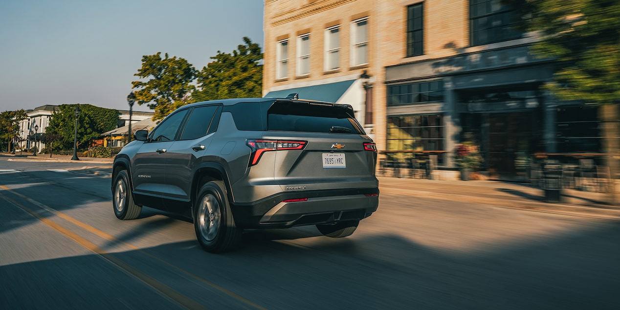 Vue latérale arrière du Chevrolet Equinox LT 2026 en gris sterling métallisé en mouvement en ville.