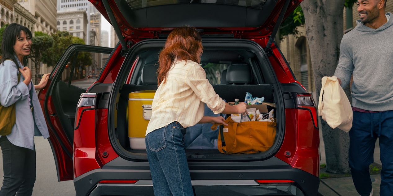 Three people stowing their bags on the trunk of the 2026 Chevrolet Equinox.