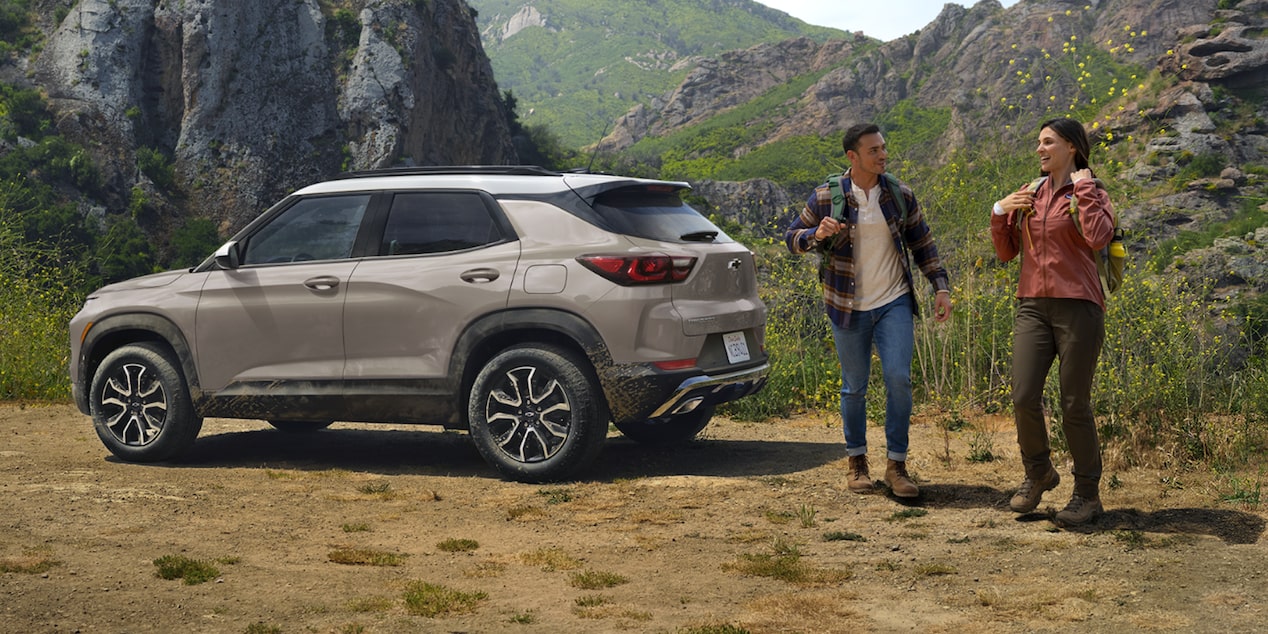 Two people walking past a 2026 Chevrolet Trailblazer parked in a hilly area.