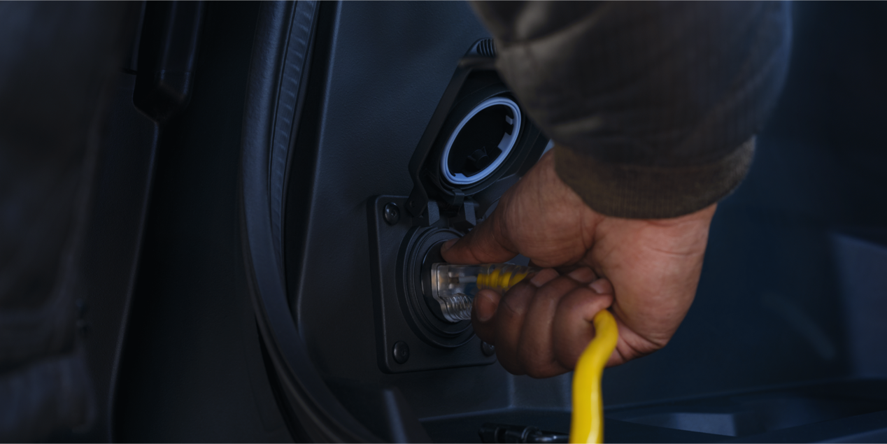 A person plugging in a power cord into a 2025 Chevrolet Silverado EV.