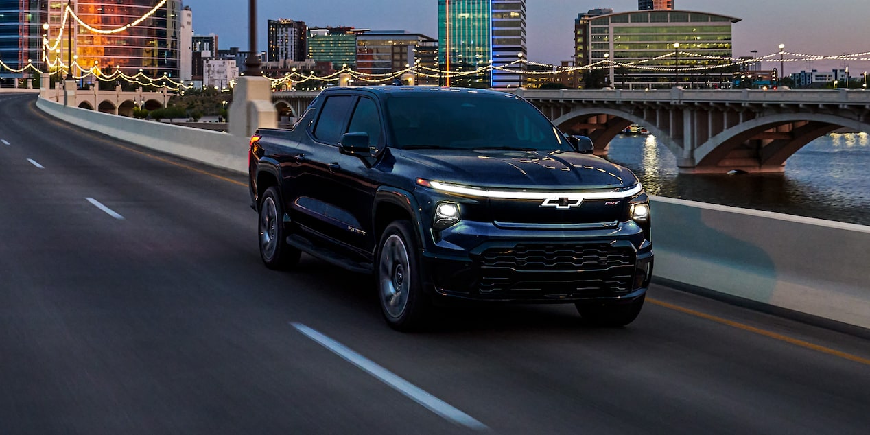 Vue latérale avant du Chevrolet Silverado EV 2025 sur la route en soirée.