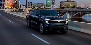 Vue latérale avant du Chevrolet Silverado EV 2025 sur la route en soirée.