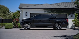 Vue latérale du Chevrolet Silverado EV 2025 devant une maison entourée d’arbres.