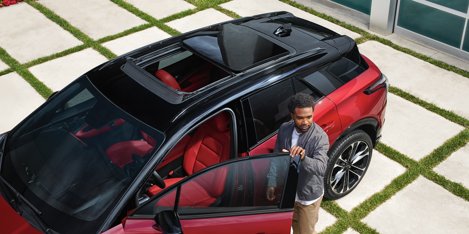 A man entering a 2026 Chevrolet Blazer EV while parked in the driveway.