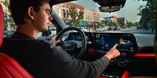 A person pressing the infotainment screen inside the 2026 Chevrolet Blazer EV.