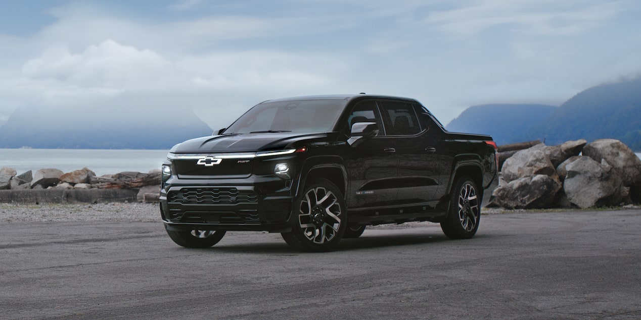 Chevrolet Silverado EV parked by a snowy mountain.