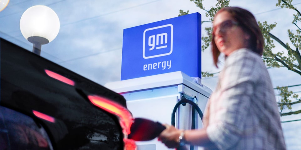 A woman charging the Silverado EV at a charging station.
