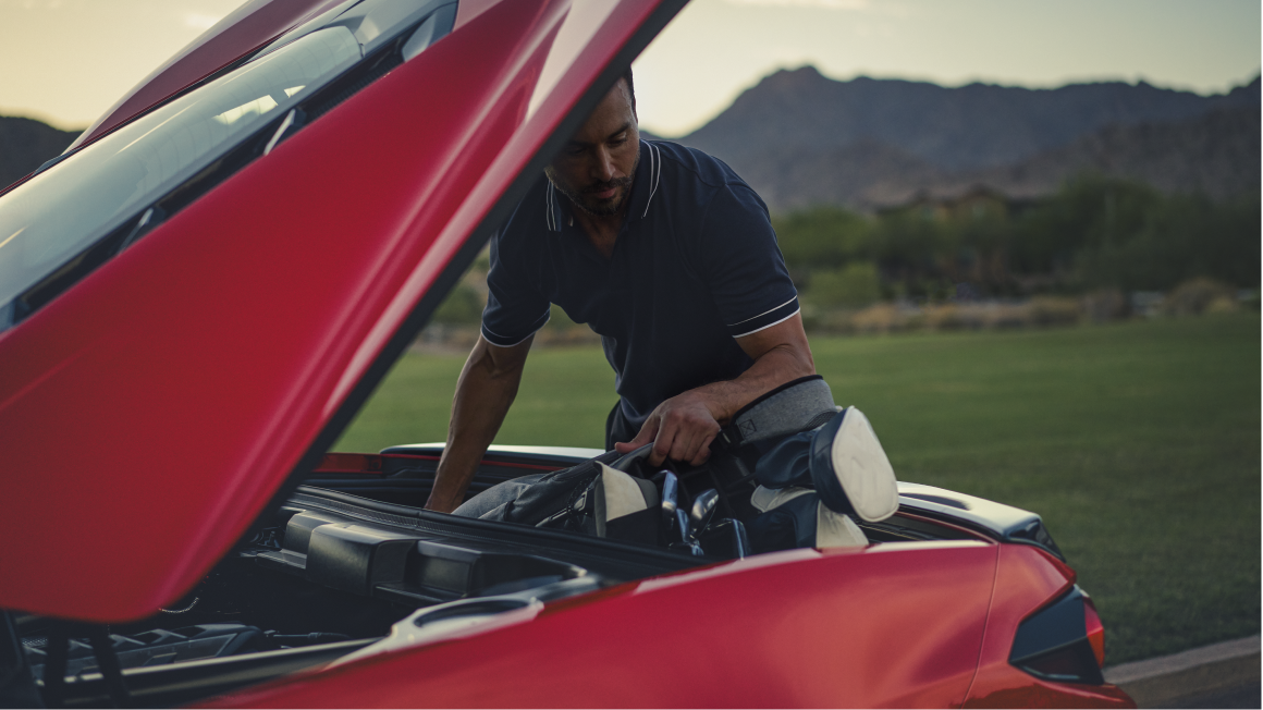 Vue latérale d’une personne qui ouvre le compartiment de rangement arrière de la Chevrolet Corvette Stingray 2025.