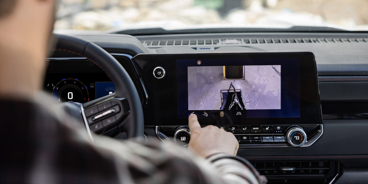 A driver interacting with the infotainment screen while driving in a 2025 Chevrolet Colorado.