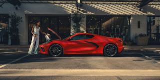 Side profile shot of a red Corvette Stingray parked on the street with frunk open