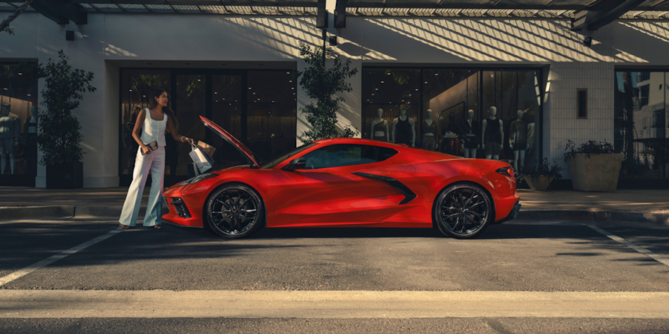 Side profile shot of a red Corvette Stingray parked on the street with frunk open