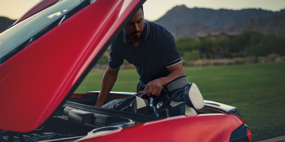 Man placing Golf clubs into the trunk of the Corvette Stingray