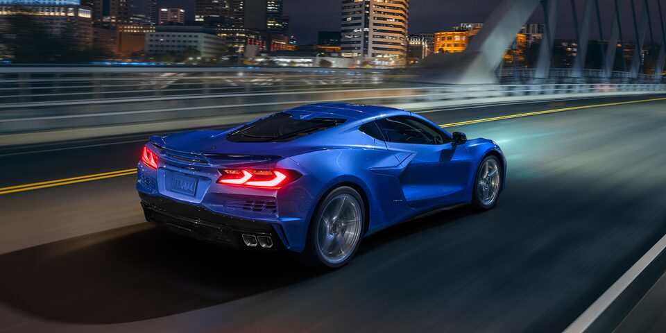 2024 Chevrolet Corvette E-Ray Driving at Night on Bridge with Cityscape in Background
